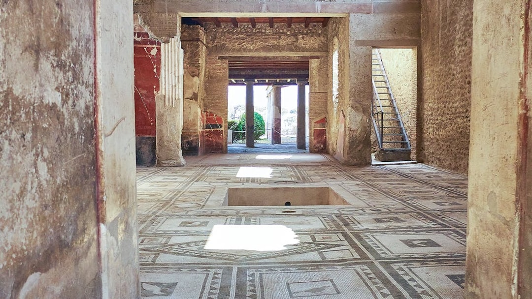House of the Tragic Poet interior with mosaic floor and ancient columns in Pompeii.
