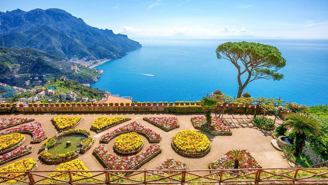 Terraced gardens overlooking the Amalfi Coast in Ravello, Italy, with views of the sea and mountains.