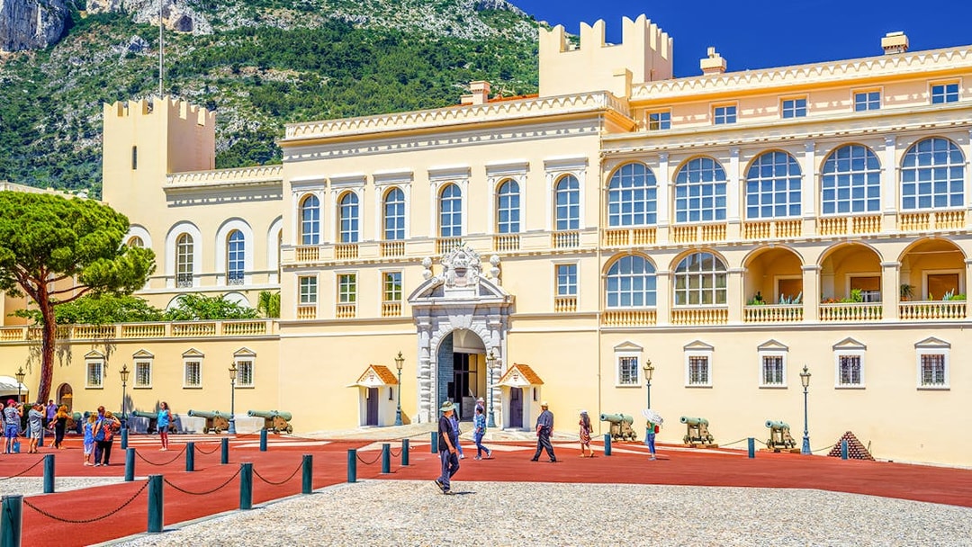 Prince's Palace in Monaco with tourists walking in the courtyard.