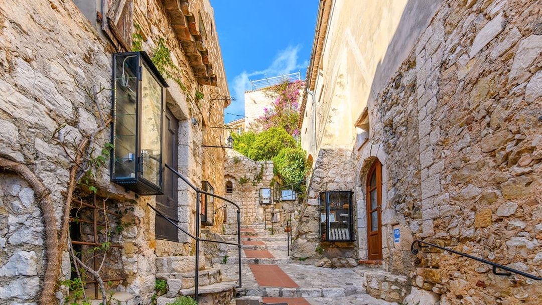 Cobblestone street in Eze, France, with tourists exploring medieval village.
