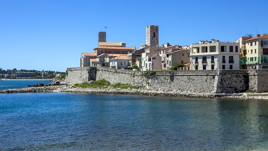 Coastal view of Antibes with historic stone buildings and fortifications by the sea.
