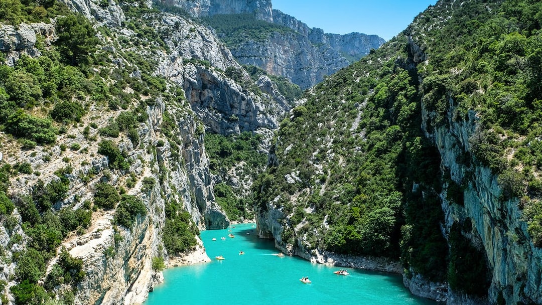 Kayakers navigating turquoise waters in Verdon Gorges, surrounded by steep cliffs and lush greenery.