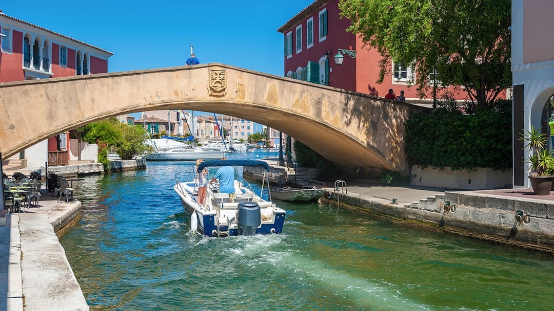 Boat passing under a stone bridge in Port Grimaud during St Tropez sightseeing tour.