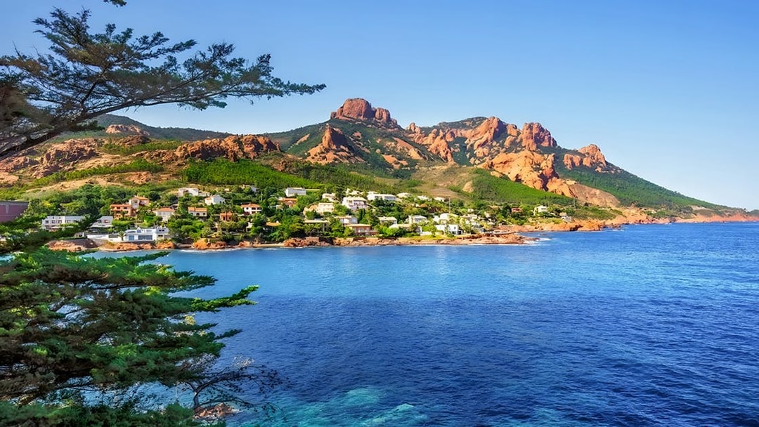 Coastal view of St Tropez with red cliffs and blue sea on the day tour from Nice.
