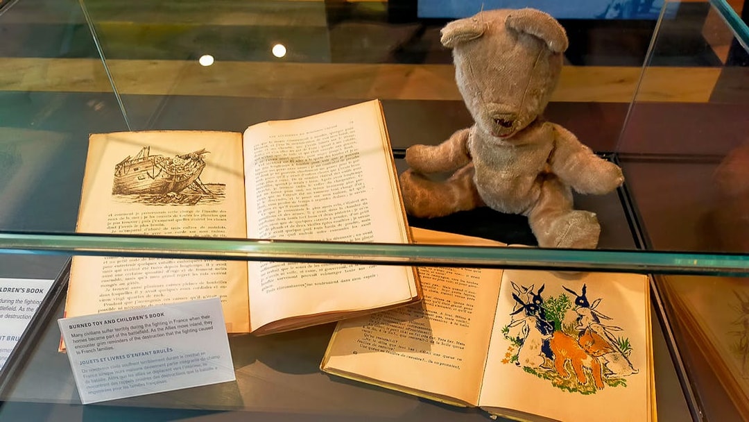 Burned toy and children's books displayed at D-Day Normandy museum exhibit.