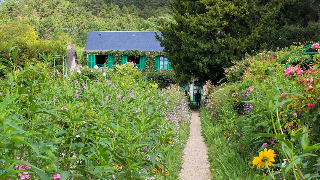 Pathway through Monet's garden leading to his house in Giverny, surrounded by vibrant flowers.