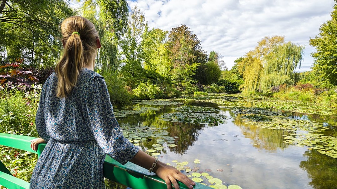 Visitor admiring water lilies at Monet's Gardens in Giverny during a half-day tour from Paris.