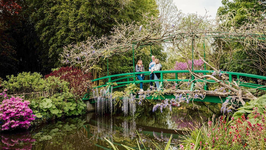 Visitors on Monet's Japanese bridge in Giverny garden during Musée d'Orsay tour.