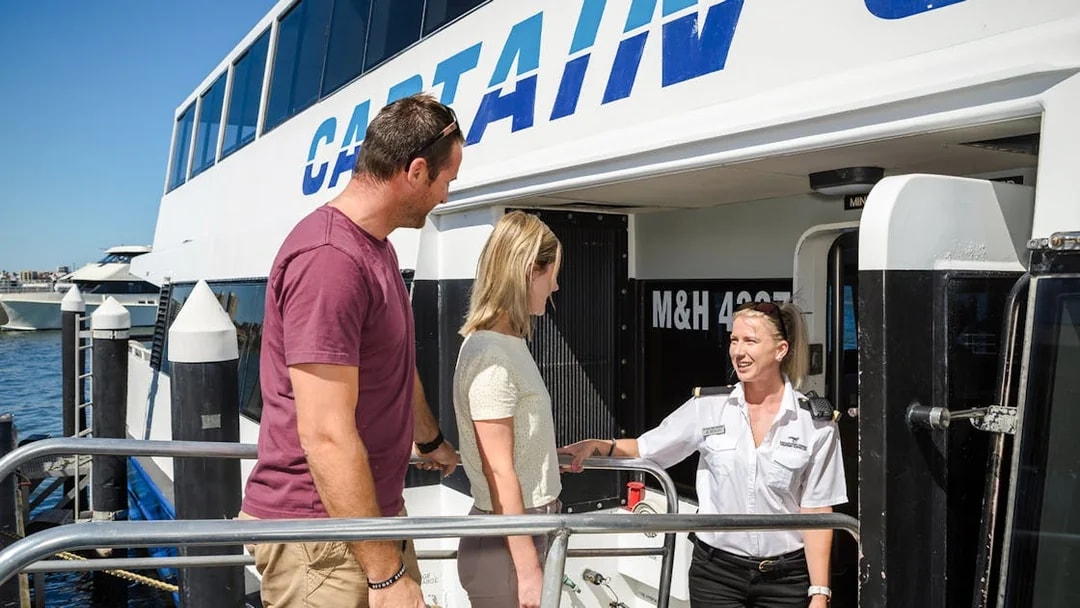 Captain Cook Cruises staff welcoming passengers aboard at the dock.