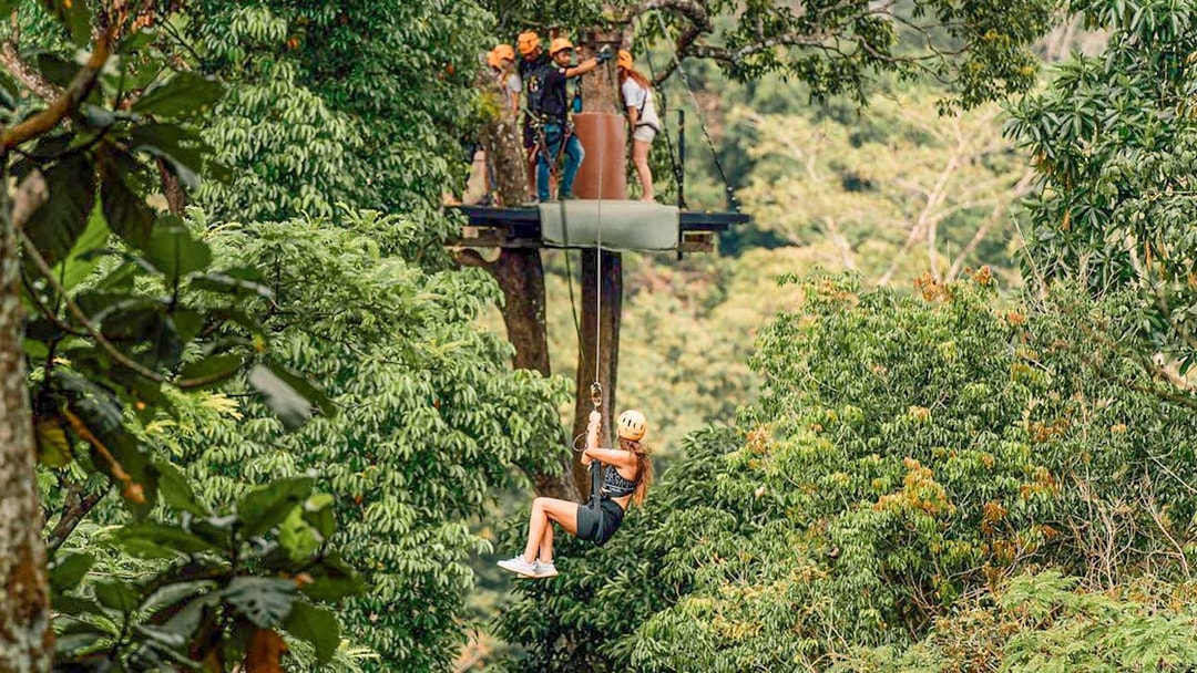 Person ziplining through lush forest in Phuket during ATV adventure tour.