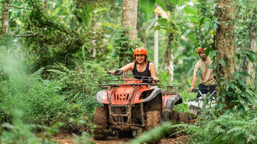 Asian couple riding ATVs through a forest track at an ATV arena.