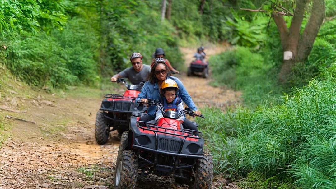 Tourists riding ATVs through lush green trails near Phuket.