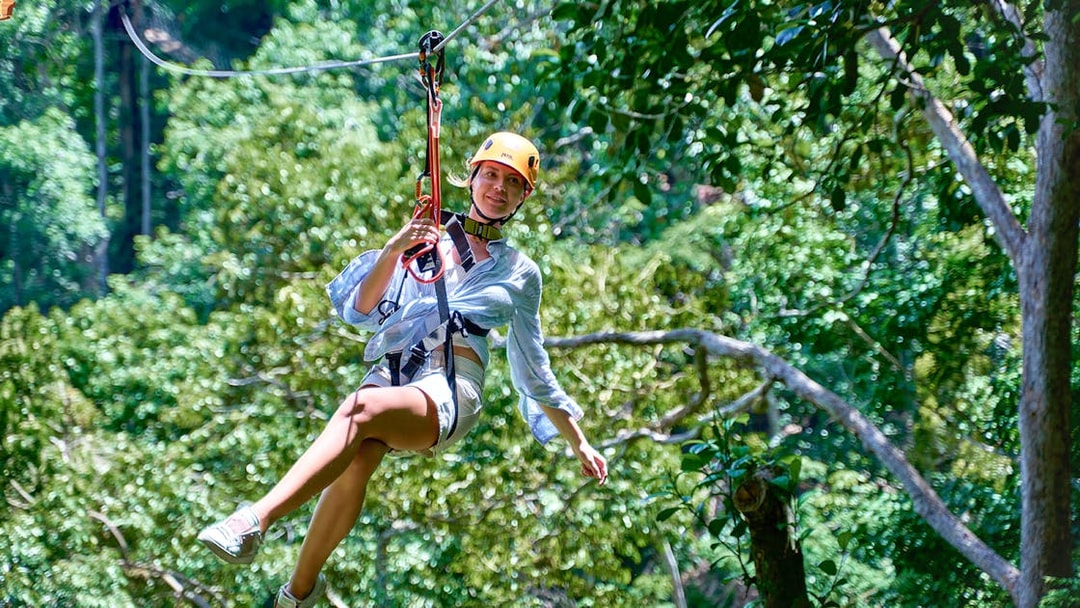 Person ziplining through lush forest at Erawan Patong Seaview in Phuket.