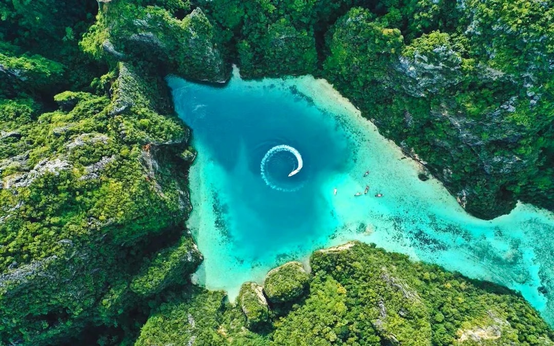 Aerial view of turquoise lagoon surrounded by lush cliffs in Phi Phi Islands, Thailand.
