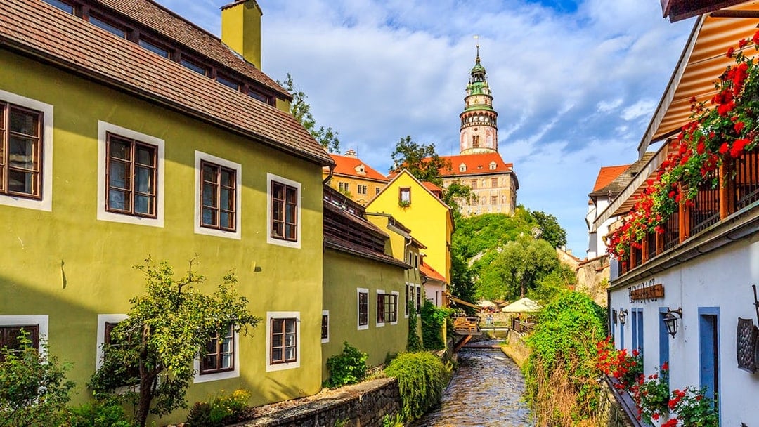 Cesky Krumlov castle tower and colorful buildings along a canal.