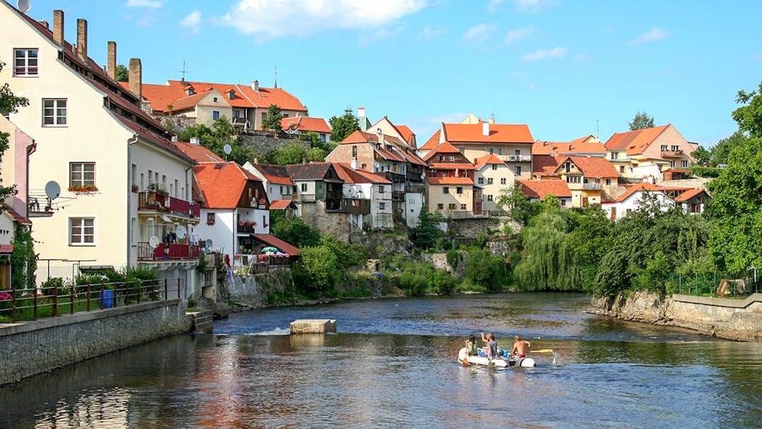 Cesky Krumlov river with people rafting, historic buildings in the background.