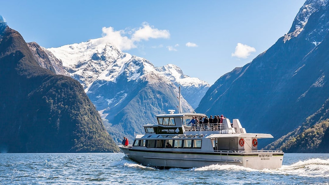 Cruise ship sailing at Milford Sound with Mitre Peak in the background, New Zealand.