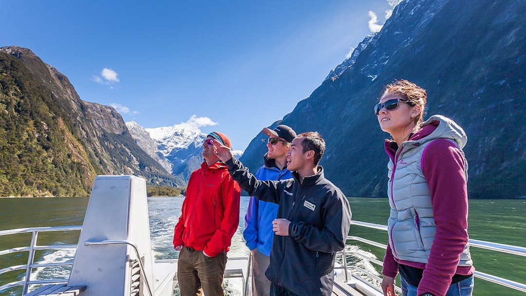 Tourists on a boat tour at Milford Sound with scenic fjord views.