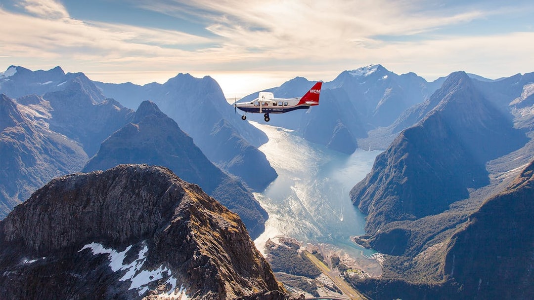 Aerial view of Milford Sound with a cruise ship below, scenic flyover from Queenstown.