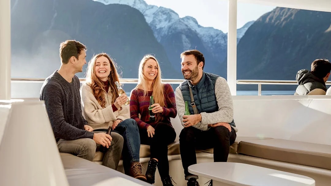 Group enjoying Milford Sound cruise with mountain views, part of Queenstown day trip.