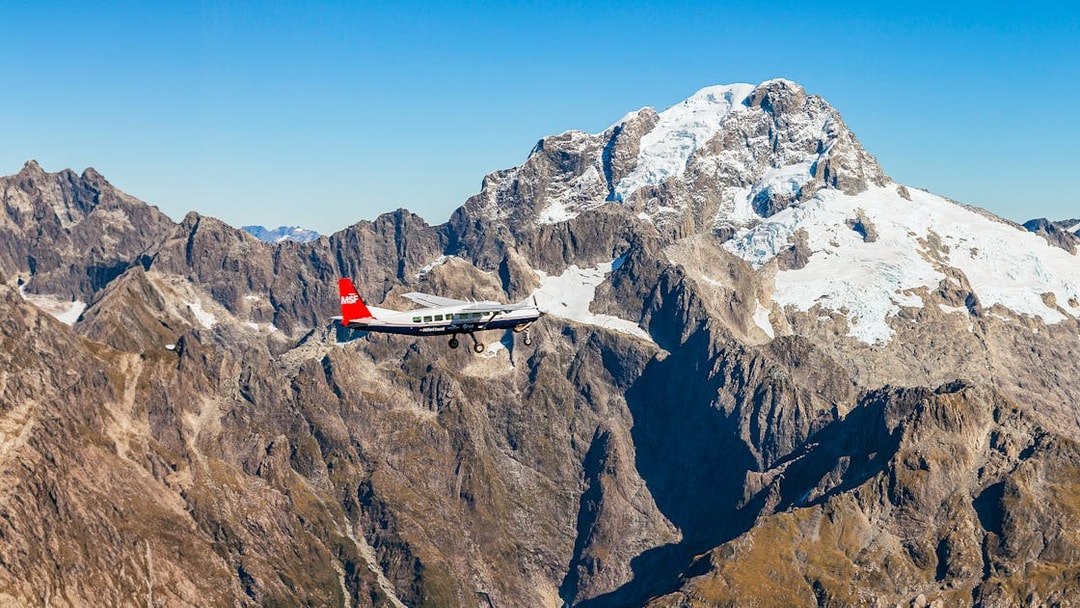 Small plane flying over snow-capped mountains during Milford Sound scenic flyover from Queenstown.