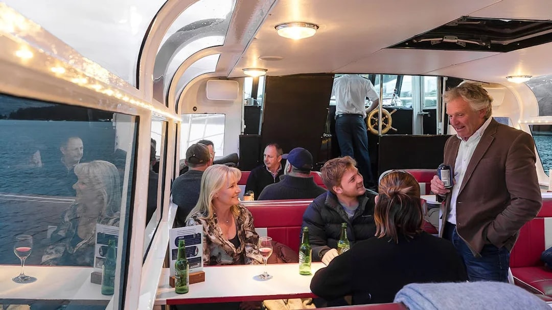 Passengers socializing in the indoor cabin during a Lake Wakatipu cruise, Queenstown, New Zealand.