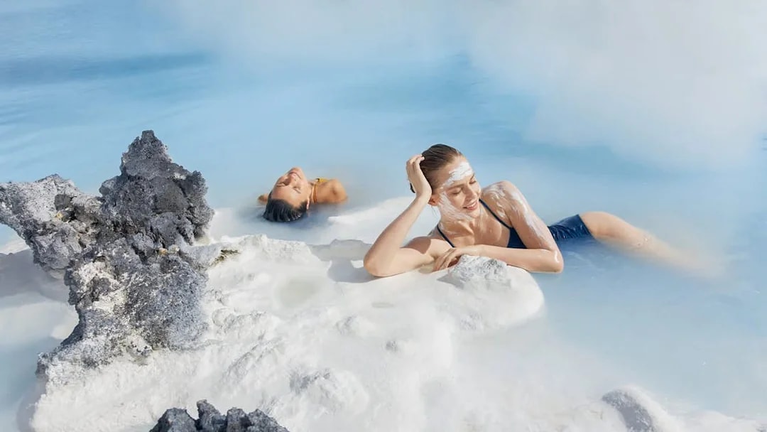 Female tourist relaxing in Blue Lagoon, Iceland, with silica mud on face.