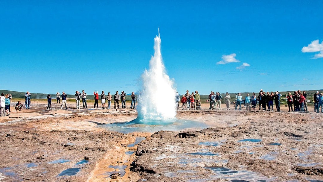 Geyser eruption at Strokkur, Iceland, with tourists observing during Golden Circle tour.