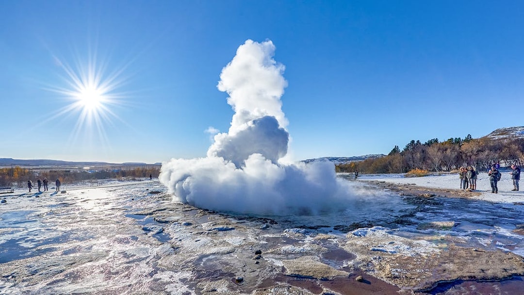 Strokkur Geyser erupting with steam in Iceland's geothermal area under a clear blue sky.