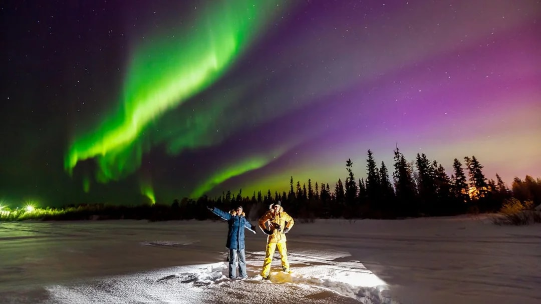 Tourist and guide viewing Northern Lights in Tromso, Norway.