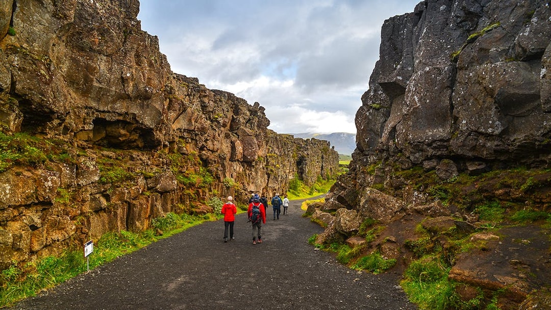 Tourists hiking through rocky landscape in Þingvellir National Park, Iceland.