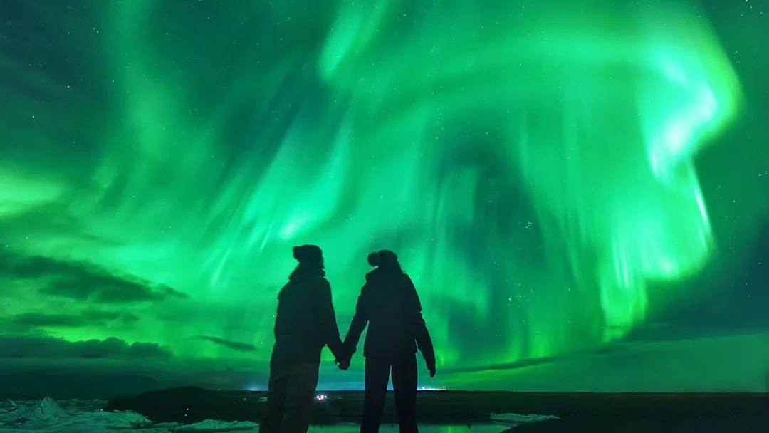 Tourists viewing Northern Lights in Iceland's night sky.