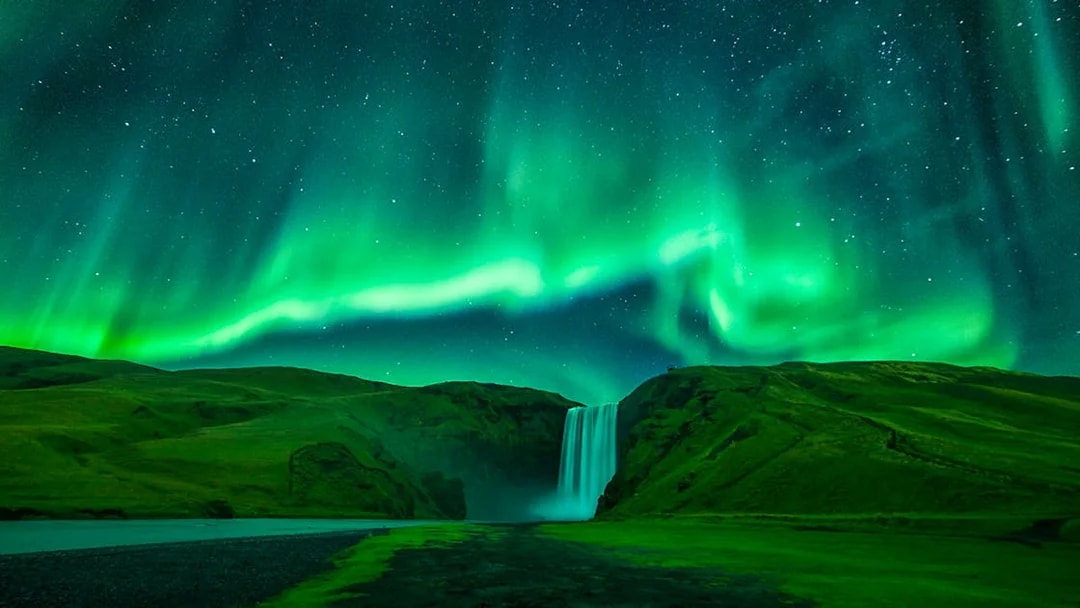 Northern lights over Skógafoss waterfall during Northern Lights Sightseeing Bus Tour.