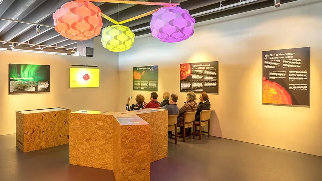Exhibit on Northern Lights with seated visitors in Reykjavik museum.