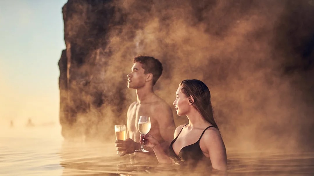 Couple enjoying drinks in the warm waters of Sky Lagoon Saman Pass.