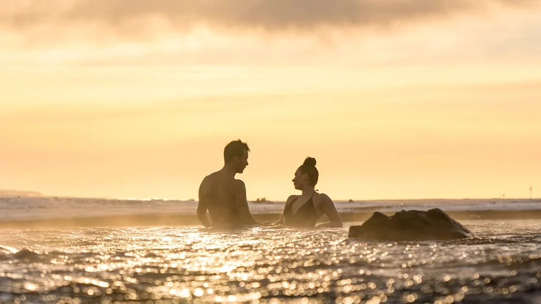 Couple relaxing in Sky Lagoon at sunset, Saman Pass tour.