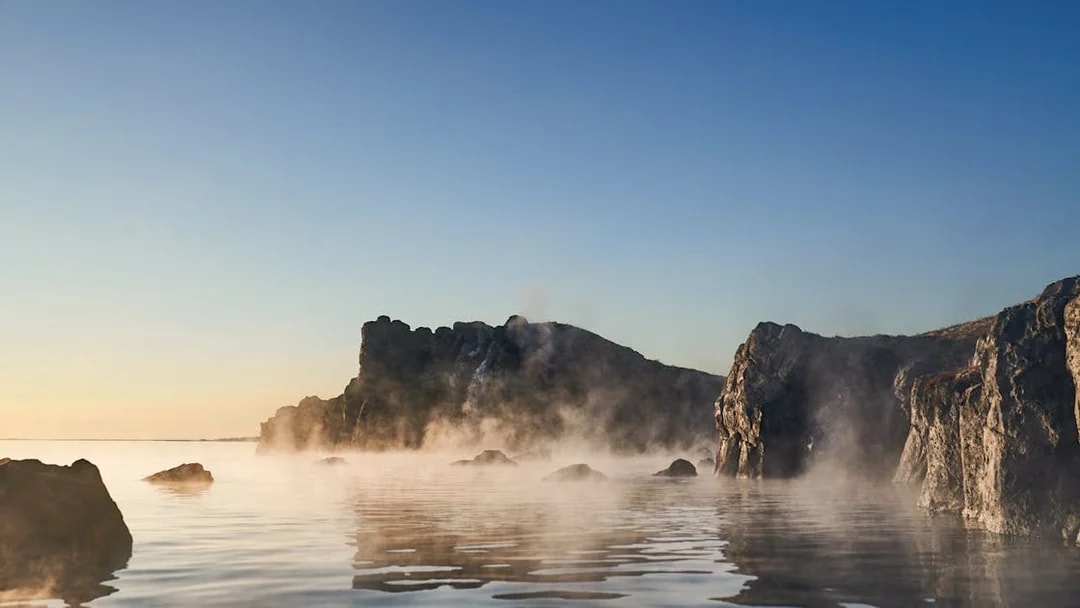 Sky Lagoon with mist rising from water, rocky cliffs in Saman Pass.