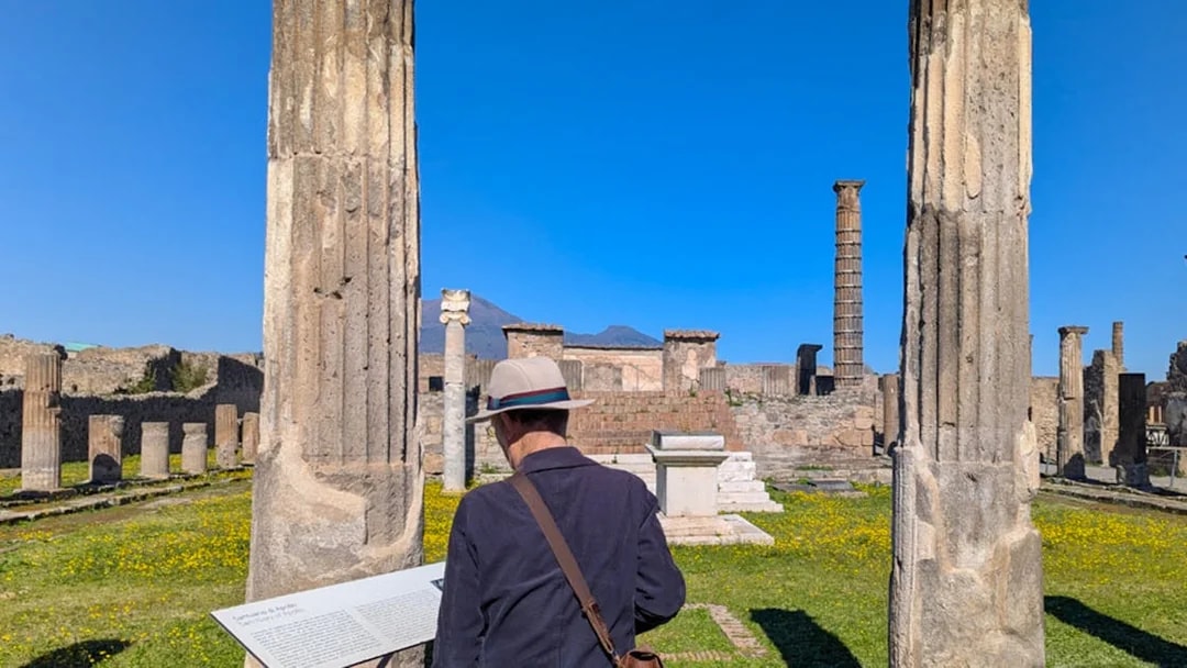 Man reading plaque at Temple of Apollo ruins in Pompeii, Italy.