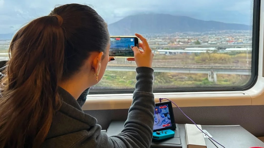 Woman photographing landscape from train window with a smartphone.