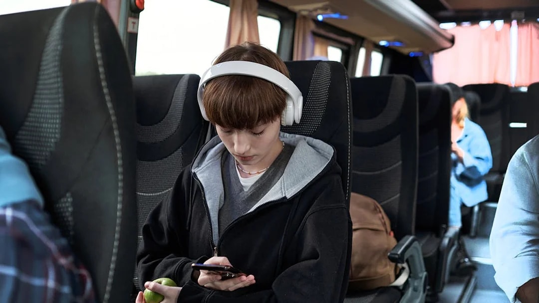 Young girl with headphones using phone on bus from Pisa to Florence.