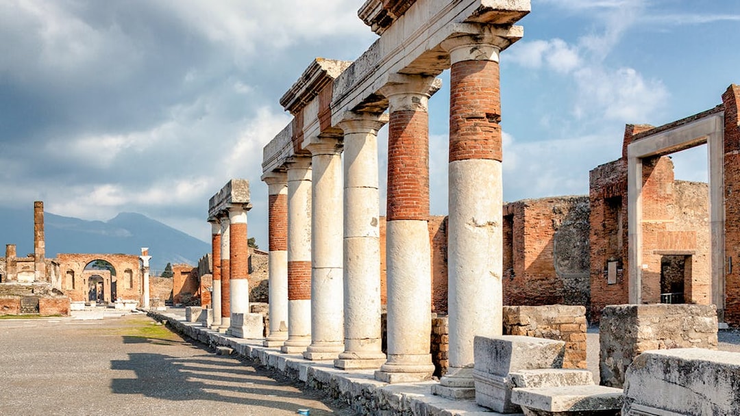 Eumachia building ruins in Pompeii with Mount Vesuvius in the background, Rome to Amalfi Coast day trip.