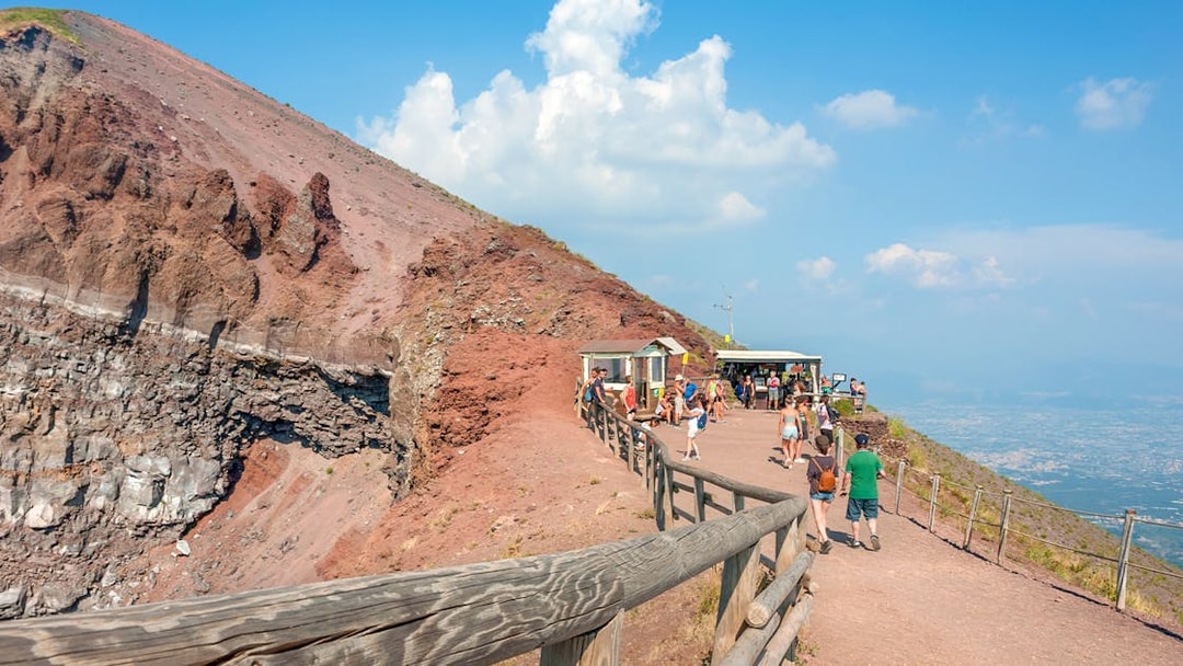 Visitors walking along the Mount Vesuvius crater path with a view of Naples.