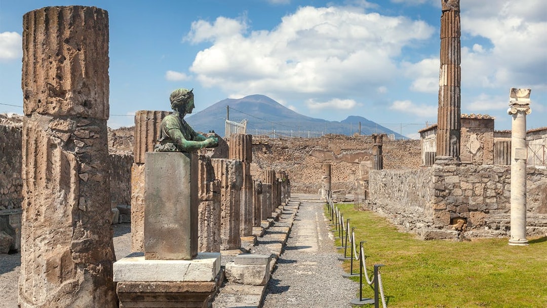 Tourists walking through ancient ruins of Pompeii with Mount Vesuvius in the background, Italy.