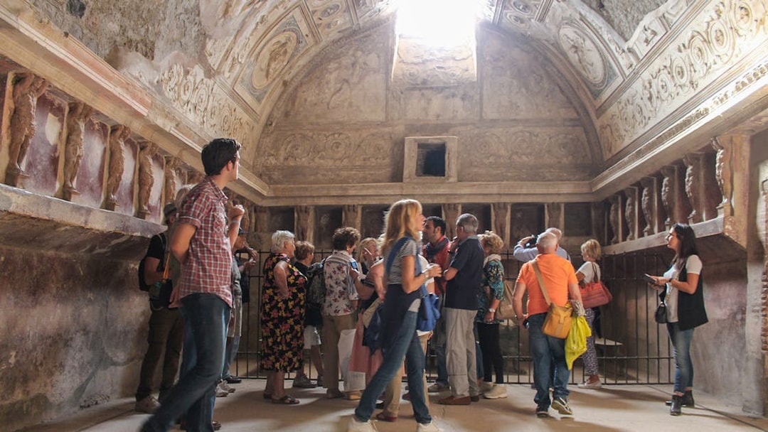 Tourists with a guide exploring an ancient room in the ruins of Pompeii, Italy.