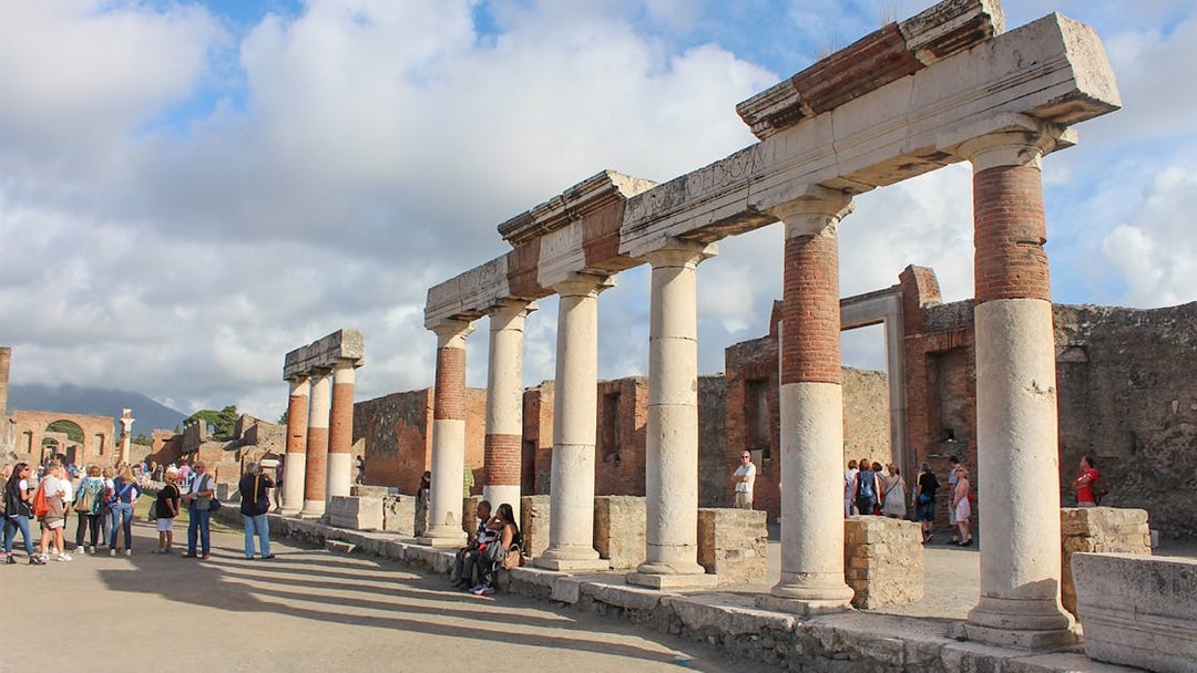 Ancient ruins with columns in Pompeii, Italy, with tourists exploring the site.