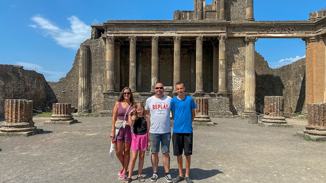 Family standing in front of ancient ruins in Pompeii, Italy.