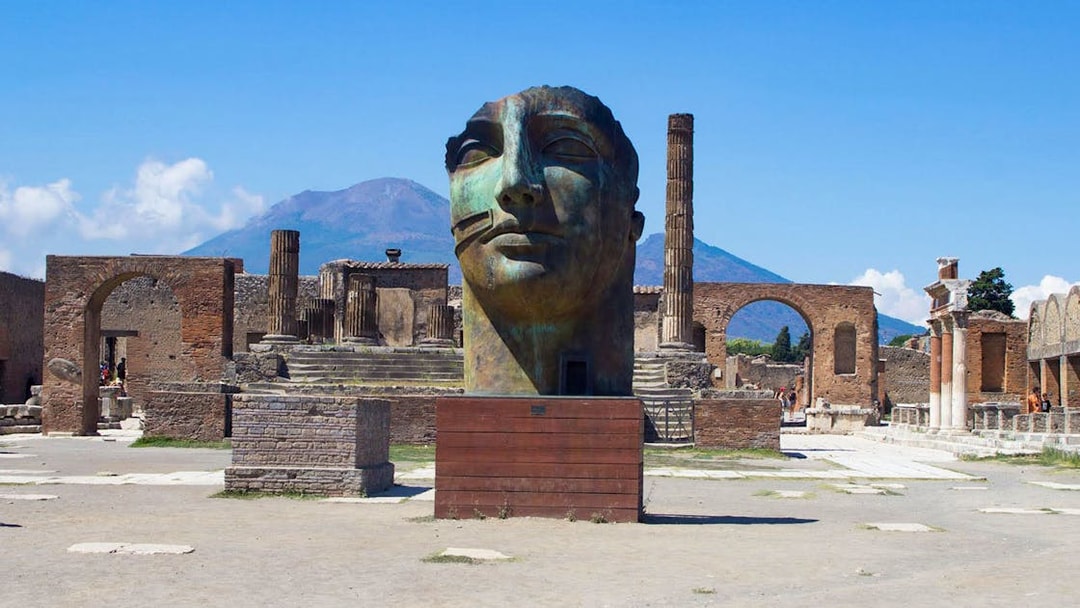 Ancient Pompeii ruins with large sculpture and Mount Vesuvius in background, Naples, Italy.
