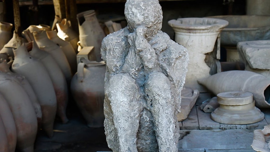 Pompeii plaster cast of a victim with amphorae in the background, Italy.