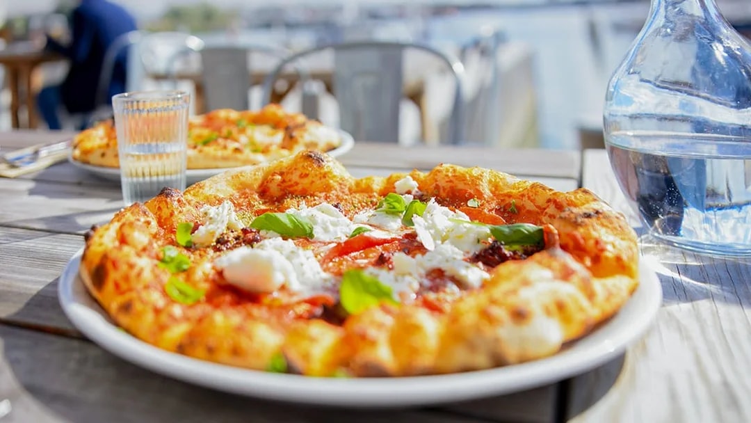 Pizza on table with view of Bay of Naples during Pompeii tour lunch.