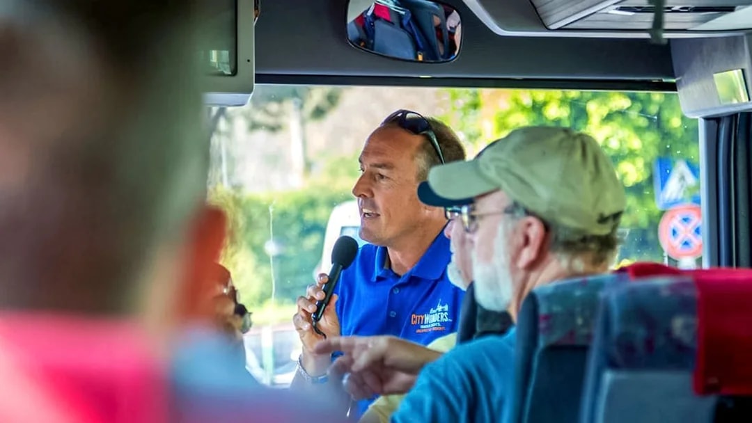 Tour guide speaking to passengers on a bus during Pompeii and Positano day trip from Naples.